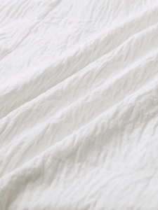 Close-up of white seersucker fabric texture on a summer A-line backless dress
