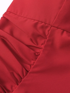 Close-up of red ruched fabric detail with fine texture on backless midi dress