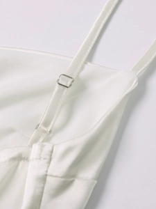 Close-up of white matte satin dress with adjustable silver buckles on thin straps