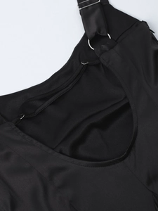 Détail de robe en satin noir avec anneaux métalliques et fines bretelles délicates