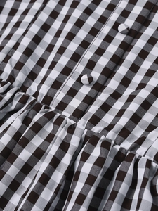 Detail of summer halter dress with brown checkered fabric and fabric-covered buttons