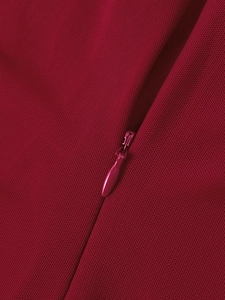 Détail d'une fermeture éclair invisible sur une robe rouge foncé montrant les coutures