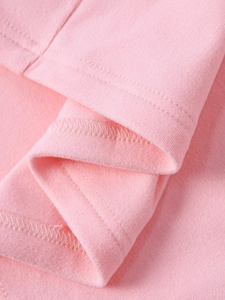 Close-up of pink knitted fabric with clean double-needle stitching and overlock seams