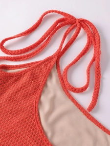 Detail of coral orange knit dress featuring honeycomb mesh texture and tie-up design
