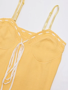 Detail of yellow knit dress featuring adjustable straps and white decorative lace-up ties