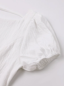Close-up of white dress showing textured puff sleeves and elastic cuff details