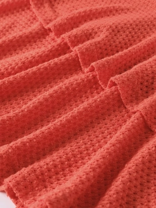 Macro shot of coral red waffle knit fabric with breathable hollow out detail layers