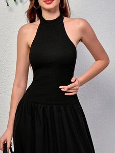Détail d'une robe en maille dos nu noire avec coupe ajustée et jupe évasée à plis élégants