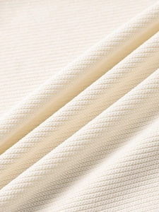 Macro shot of cream-colored knit fabric texture with high-quality twill pattern detail