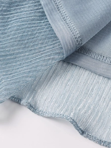 Detailed macro shot of light blue metallic pleated fabric with silver shimmering texture