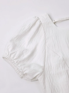 Detail of white puff sleeve dress featuring crinkle texture fabric and elastic cuffs