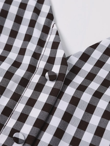 Macro detail of V-neck gingham dress featuring fabric-covered buttons and fine stitching