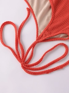 Detailed close-up of red crochet knit texture and tie-up design on the beach dress