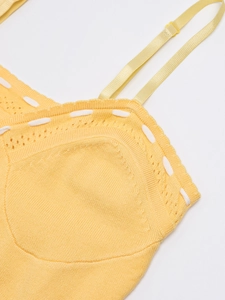 Detailed close-up of yellow knit dress fabric with white decorative stitching and strap