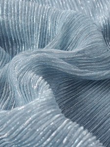 Detailed macro view of light blue metallic pleats with sparkling silver thread texture