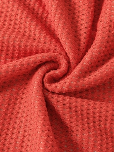 Macro detail of breathable red waffle knit mesh fabric with honeycomb texture and soft drape