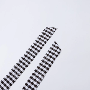Detail view of black and white checkered narrow silk scarves with diagonal edge finish