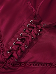 Detailed close-up of matte satin fabric with criss-cross lacing and hollow-out mesh edges
