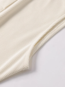 Detail shot of the cream ribbed knit dress showing the precise stitching and texture