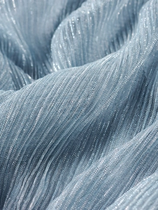 Detailed close-up of light blue metallic pleats with shimmer texture and luxury finish