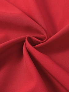 Detailed macro view of the red twill fabric texture and draped folds of the midi dress