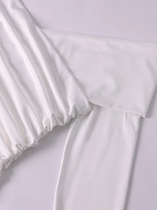 Detail view of white milk silk dress showing ruched pleated fabric texture and sleek seams