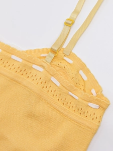 Detail of yellow knit dress featuring hollow patterns and adjustable straps