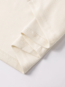 Detailed macro view of the ribbed knit hem and neat inner stitching on a cream dress