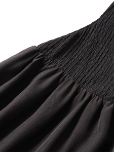 Détail d'une robe noire en maille avec smocks délicats et texture plissée élastique de qualité