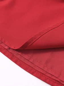 Detailed macro view of the professional double stitching and hem on the red fabric dress