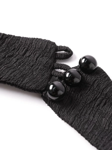 Détail macro d'une robe en maille noire avec texture gaufrée et trois boutons sphériques