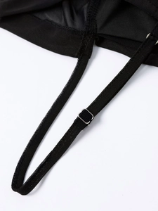 Detail view of the adjustable mesh shoulder strap with silver buckle on black dress
