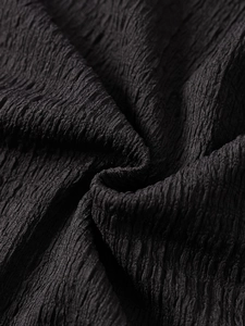 Vue macro détaillée de la texture du tissu plissé noir d'une robe tricotée dos nu