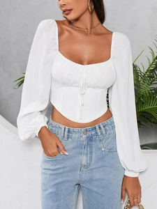 Detail of white crop top featuring sweetheart neckline, ruched bust, and puff sleeves