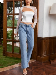 Dettaglio del crop top in pizzo bianco con maniche in rete floreale e bordo in pizzo