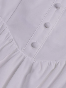 Detailed view of white lace dress featuring delicate fabric buttons and pleated texture