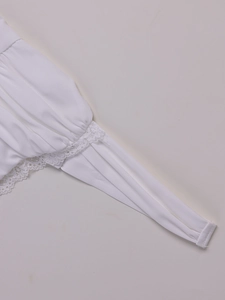 Close-up of white dress showing intricate lace trim and pleated fabric details