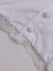 Detailed close-up of white lace trim and fabric buttons on an A-line strap dress