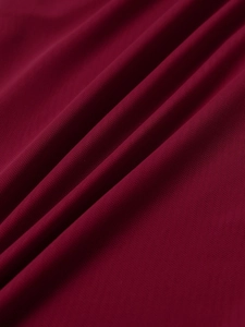 Detailed macro shot of dark red mesh fabric texture with elegant pleated draping
