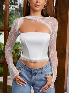 Dettaglio del corsetto in raso bianco con maniche in pizzo velato e tagli asimmetrici