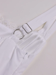 Close-up of white lace trim, pleated fabric, and metal strap buckle on a slip dress