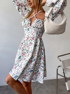Detail eines weißen Blumenkleides mit Neckholder-Bindung und Puffärmeln