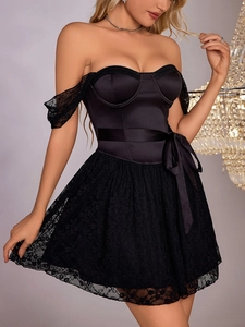Detail of black corset mini dress featuring lace floral hem and satin ribbon bow at the waist
