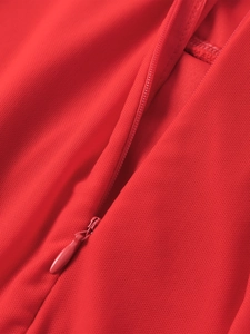 Détail d'une robe en maille rouge avec fermeture éclair invisible et tissu texturé