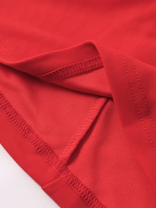 Détail macro de la robe en résille rouge avec ourlet à double surpiqûre et texture piqué