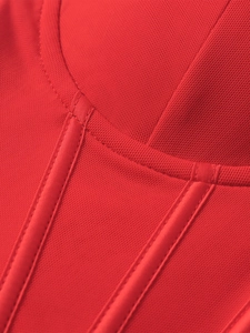 Détail du tissu en maille rouge et des coutures de baleines en satin sur une robe