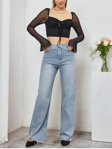 Detail of black mesh long sleeve crop top with lace-up front and high-waist jeans