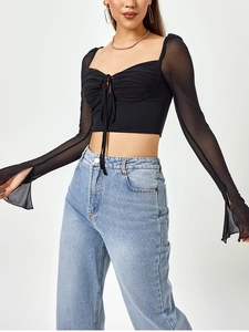 Detail of black mesh long sleeves and lace-up ruched front on this sexy crop top