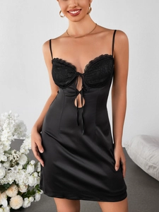 Détail d'une robe en satin noir avec bonnets en dentelle et décoration de nœud délicate