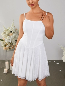 Detail of white lace corset dress with delicate floral backdrop and adjustable straps